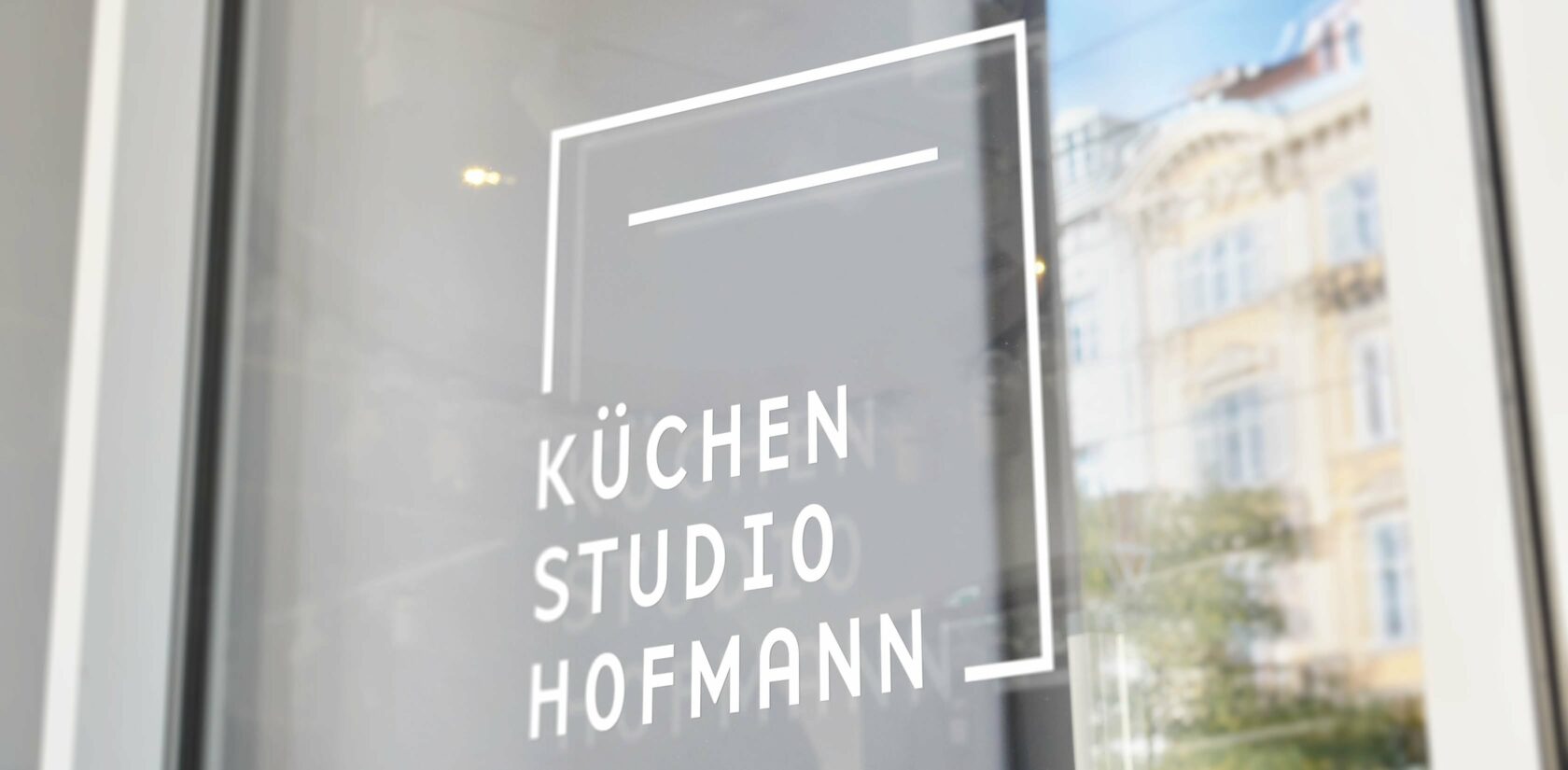 Bild von dem Logo vom Küchenstudio Hofmann auf einem Fenster