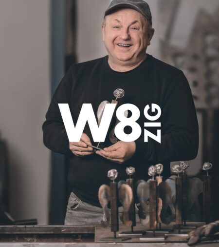 lächelnder Mitarbeiter mit einem Metallengel in der Hand. Darüber ist das Logo von W8ZIG zu sehen.