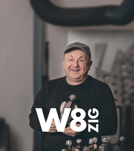 lächelnder Mitarbeiter mit einem Metallengel in der Hand. Darüber ist das Logo von W8ZIG zu sehen.