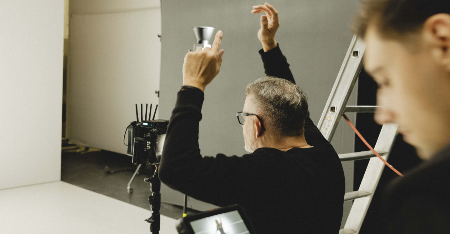 Christian Schirmers dirigiert Szene im Studio mit erhobenen Armen während Aufnahme, im Hintergrund Kamera- und Lichtequipment sichtbar
