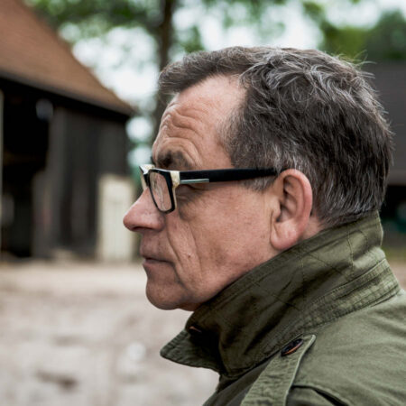 30 Jahre schirmers Geschichte. Seitenprofil von Christian Schirmers, der Gründer von schirmers. agentur. Er trägt eine grüne Jacke mit hochgestelltem Kragen, aufgenommen von dem neuen Agentursgebäude